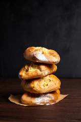 Wheat buns with curd filling on a wooden table, close-up. Bakery, four buns with cottage cheese stacked on baking paper on dark background