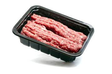 Ground beef in a black plastic tray isolated on white background. Uncooked mincemeat. Forcemeat,...