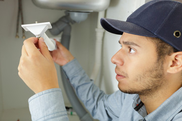 plumber fixing sink pipe with wrench in bathroom