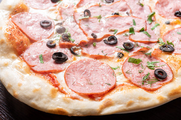 Cheap pizza with pepperoni, ham, olives and herbs.