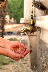 boy washing his hands in an old park fountain