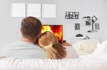 Young couple watching television at home