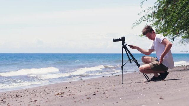DSLR camera on imbalance tripod fall down on the sand.