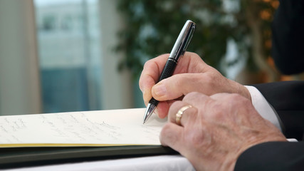 the hand of a business man signs an important document with a pen