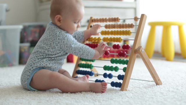Cute little baby boy, playing with abacus at home, sunny kids room