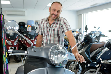 middle-aged man looking at scooter in motorcycle showroom