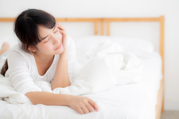 Beautiful portrait young asian woman lying and smile while wake up with sunrise at morning, girl with happy annd fun in the bedroom, lifestyle and relax concept.