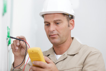 an electrician checking socket voltage