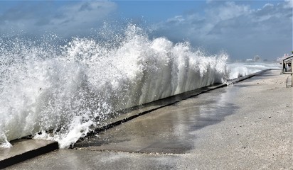 Large wave is crashing into beach wall during a stormy day in a St.Pete Beach n Florida during...