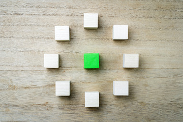 Eight square wood blocks form a circle around a green square block