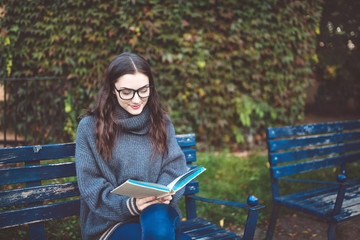 Woman reading a book on the bench in a park