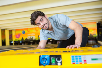 man hand picking up bowling ball from rack in club