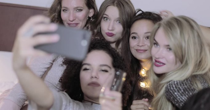 Group of girls taking selfie in bedroom at house party