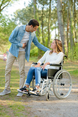 Fototapeta premium pretty woman in a wheelchair meeting man in the park