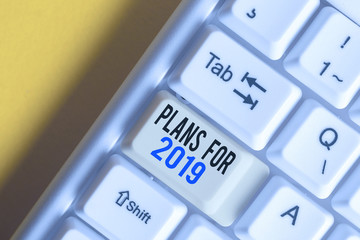 Fototapeta na wymiar Writing note showing Plans For 2019. Business concept for an intention or decision about what one is going to do White pc keyboard with note paper above the white background
