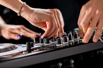 male and female DJ hands on a DJ consolle