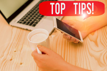 Text sign showing Top Tips. Business photo text small but particularly useful piece of practical advice woman laptop computer smartphone mug office supplies technological devices