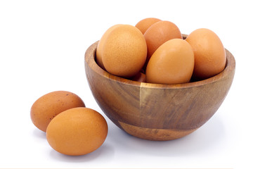 Fresh chicken eggs in a wooden bowl on a white background