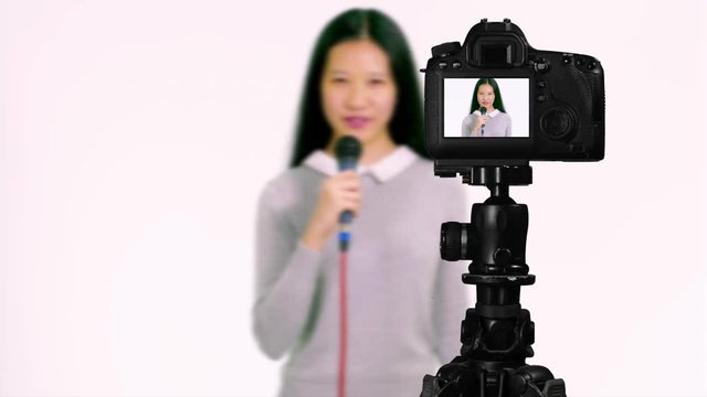 Chinese Asian American  teenager with microphone, presentingseen through camera, vlogger concept