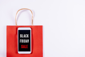 Black Friday concept. Mobile phone or smartphone with paper bag on white background. Online shopping.