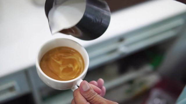 barista pouring milk to make coffee latte art. b-roll footage video 4k. cafe business shop.