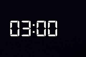 Showing time 03:00 on white led digital clock isolated black background