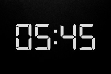 Showing time 05:45 on white led digital clock isolated black background