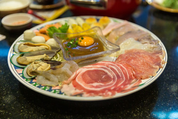Fototapeta na wymiar Sukiyaki Japanese food shabu shabu. Sukiyaki Fresh Beef pork slices, Vegetable, Dinner Set. shabu or suki yaki set in metal trey placed on table.
