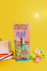 Text sign showing Strategic Plan. Business photo text a systematic process of envisioning a desired future Trash bin crumpled paper clothespin empty reminder office supplies yellow