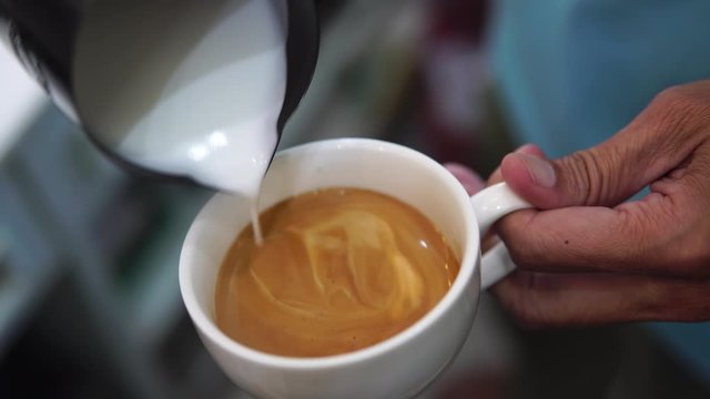 barista pouring milk to make coffee latte art. b-roll footage video 4k. cafe business shop.