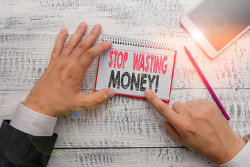 Text sign showing Stop Wasting Money. Business photo text advicing demonstrating or group to start saving and use it wisely Hand hold note paper near writing equipment and modern smartphone device
