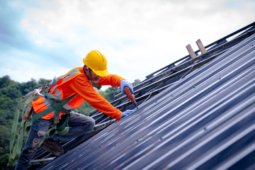 Roofer worker in protective uniform wear and gloves, using air or pneumatic nail gun and installing...