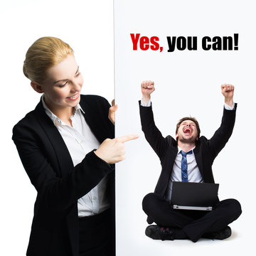 businesswoman pointing to a cardboard with a happy businessman and the slogan "yes, you can!" isolated on white