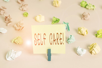 Writing note showing Self Care. Business concept for practice of taking action to preserve or improve ones own health Colored crumpled papers empty reminder pink floor background clothespin