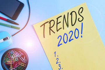 Writing note showing Trends 2020. Business concept for general direction in which something is developing or changing Notebook and stationary with gadgets above pastel backdrop