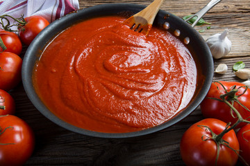 Preparing tomato sauce at home. Top view of a rustic wooden table filled with fresh ingredients for...