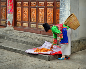 Bai woman selling loquats in the streets of Dali ancient city, Yunnan province, China.