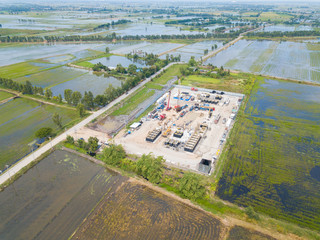 Oil and gas a land rig, onshore drilling rig, in the middle of a rice field aerial view from a drone.