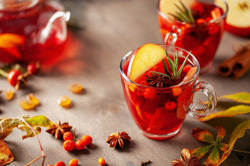Mulled wine with fruits and spices in glass on a wooden  background. Traditional hot drink at ...