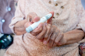 Old woman holding lancet to measure her blood sugar