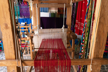 El telar de pie tiene hilo de algodón rojo, blanco y está listo para ser usado.