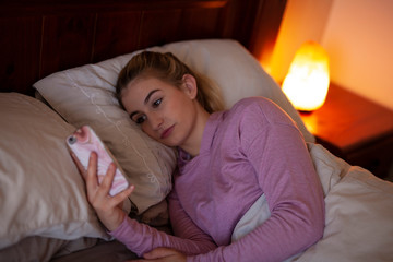 on Mobile smart phone in bed with himalayan salt lamp