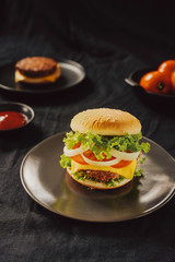 Hamburger with beef meat burger and fresh vegetables on dark background. Tasty fast food