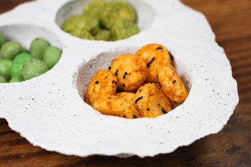 Wasabi rice snacks in a white bowl on wood background