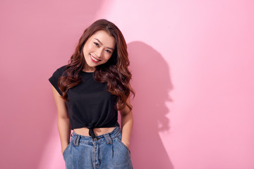 beautiful portrait Asian cheerful young girl poses in casual clothes with beaming smile standing isolated on pink background