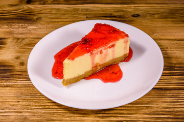 White plate with cheesecake New York and raspberry jam on wooden table