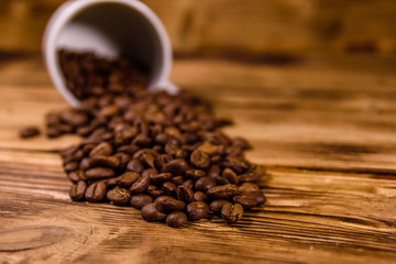 White cup and scattered coffee beans on wooden table