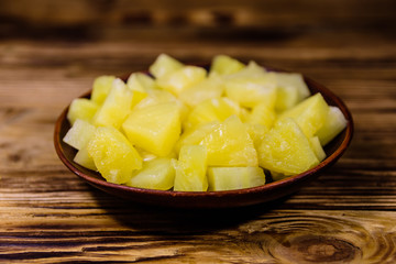 Ceramic plate with chopped canned pineapple on wooden table
