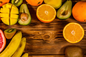 Still life with exotic fruits. Bananas, mango, oranges, avocado, grapefruit and kiwi fruits on wooden table. Top view