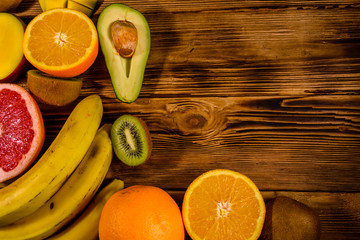 Still life with exotic fruits. Bananas, mango, oranges, avocado, grapefruit and kiwi fruits on wooden table. Top view